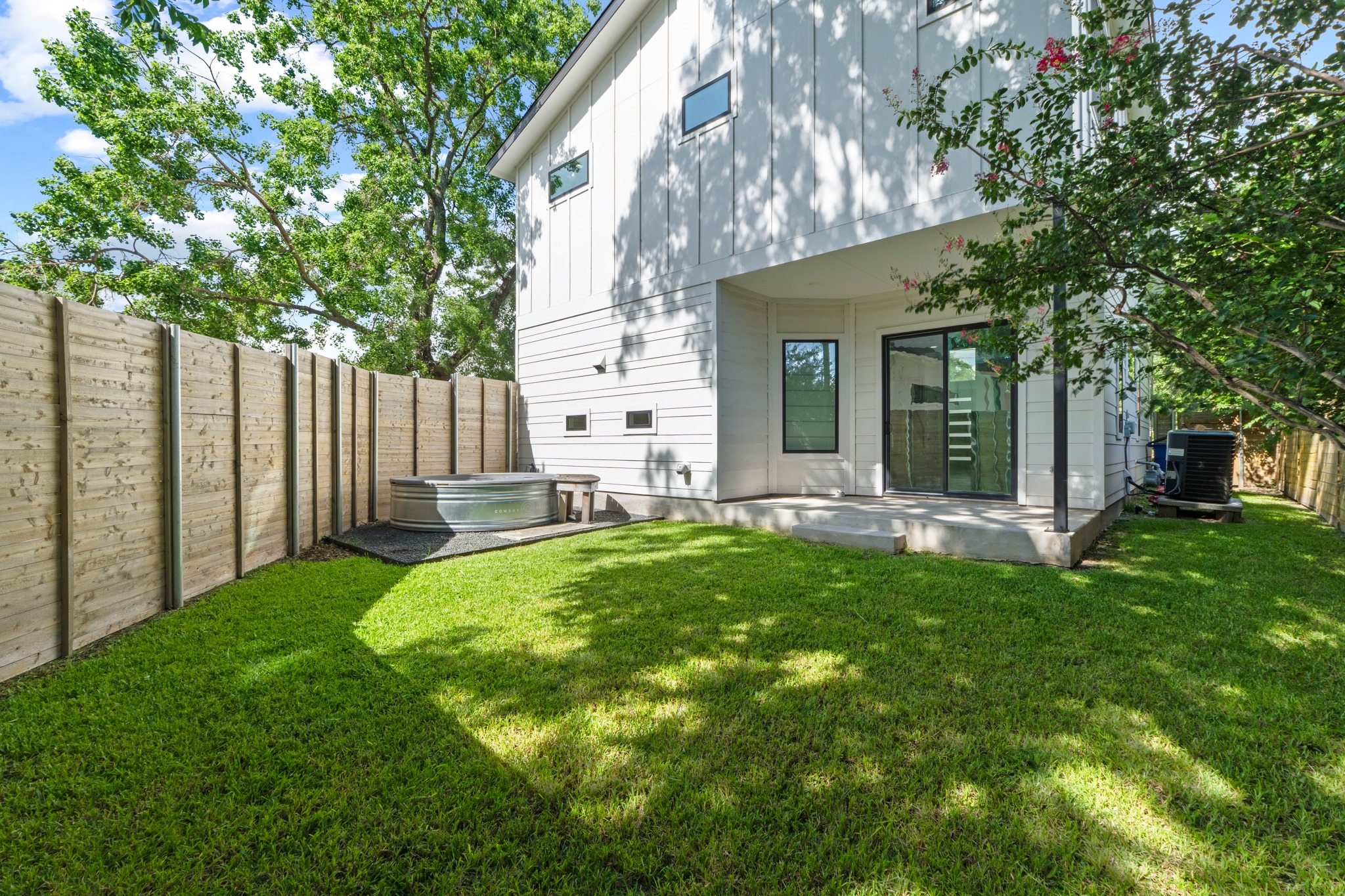 2007 Chestnut Avenue, Unit 1 Austin, TX 78722 - Photo 32 of 32 A private backyard oasis with lush green grass and a modern stock tank spa.