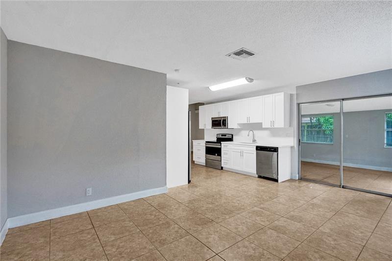 8221 Southwest 3rd Court Pompano Beach, FL 33068 - Photo 4 of 25 a kitchen with stainless steel appliances a refrigerator and white cabinets
