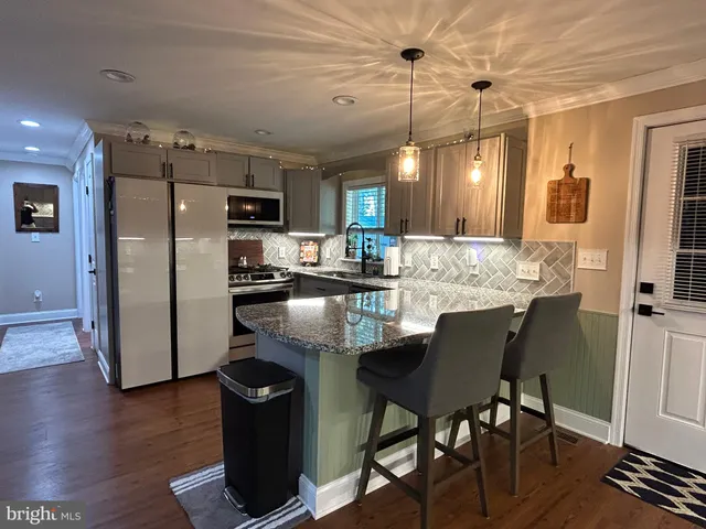 a kitchen with kitchen island granite countertop wooden floors and refrigerator