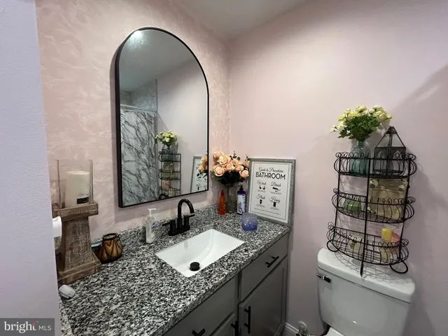 a bathroom with a granite countertop sink a toilet and mirror