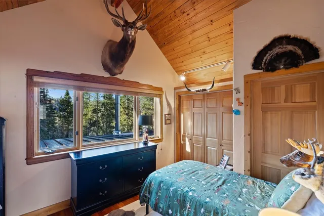 a bedroom with a large bed a flat tv screen and dresser next to a window