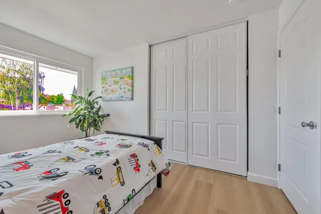 a bedroom with a bed and closet with wooden floor