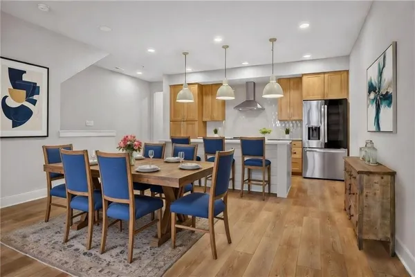 a dining room with stainless steel appliances kitchen island granite countertop a table chairs and a refrigerator