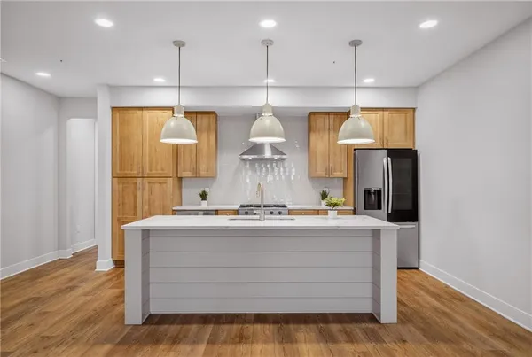 a kitchen with kitchen island stainless steel appliances wooden floor cabinets and a window