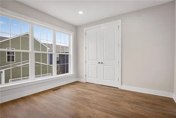 a view of an empty room with wooden floor and windows
