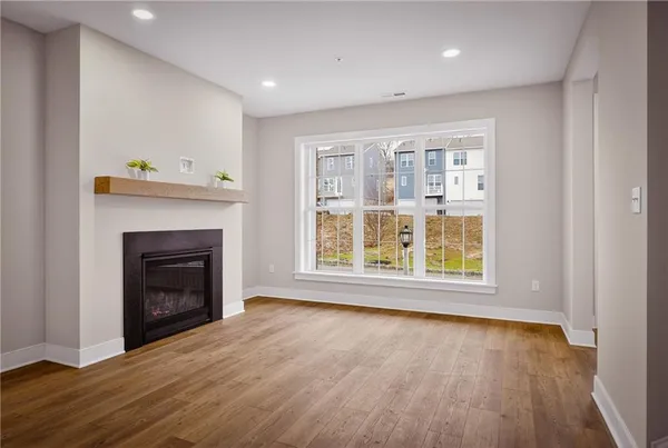 a view of an empty room with wooden floor fireplace and a window