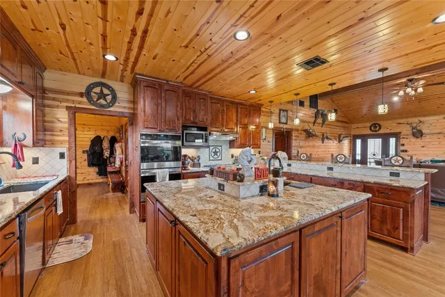 a kitchen with stainless steel appliances granite countertop a kitchen island a stove and a wooden cabinets