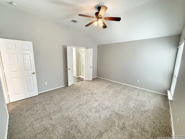 an empty room with chandelier fan and windows