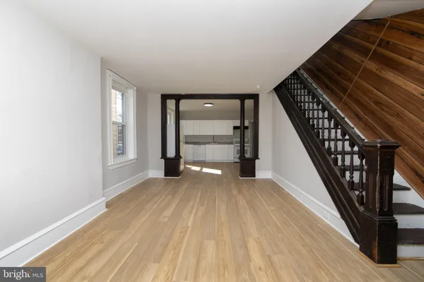 a view of an empty room with wooden floor and stairs