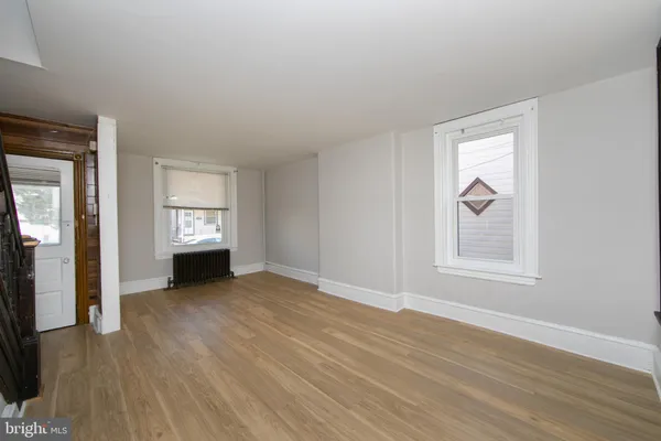 a view of an empty room with window and wooden floor