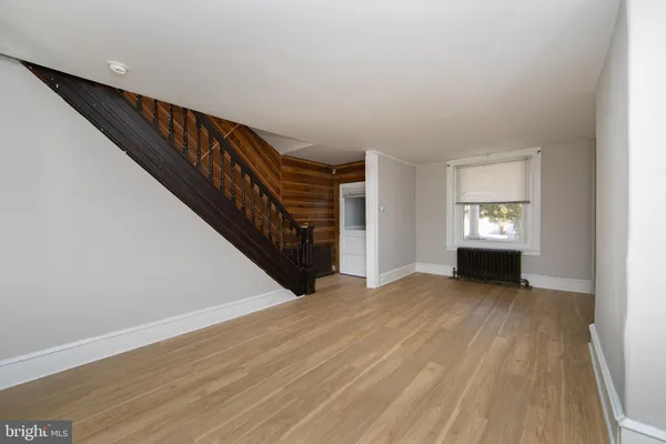 a view of an empty room with wooden floor and stairs