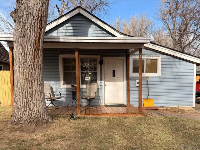 a backyard of a house with wooden fence and large tree