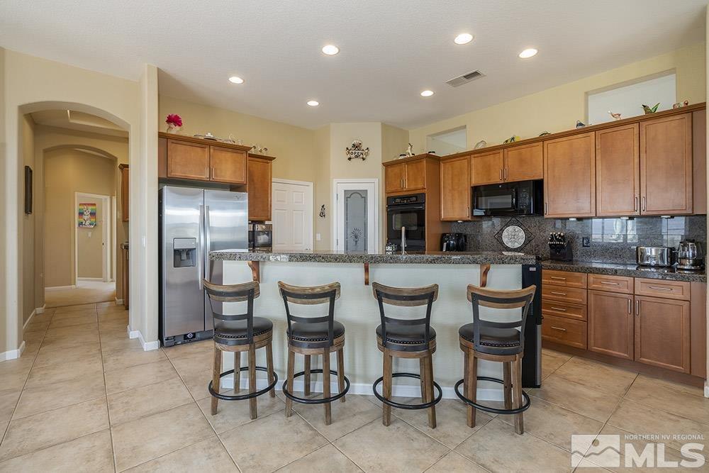 6840 Marble Canyon Road Reno, NV 89511 - Photo 7 of 39 a kitchen with stainless steel appliances kitchen island granite countertop a sink and cabinets