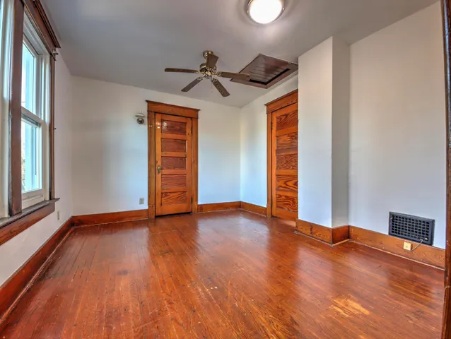 a view of empty room with wooden floor and fan