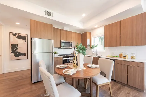 a kitchen with stainless steel appliances refrigerator dining table and chairs