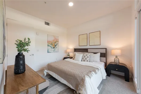 a bedroom with a bed a couch and a potted plant