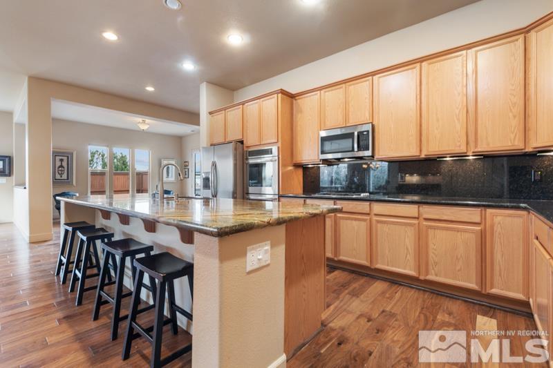 1630 Brightstone Court Reno, NV 89521 - Photo 2 of 27 a kitchen with granite countertop a stove a sink and white cabinets