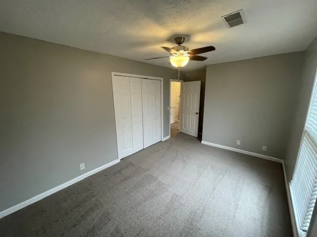 an empty room with a window and chandelier fan