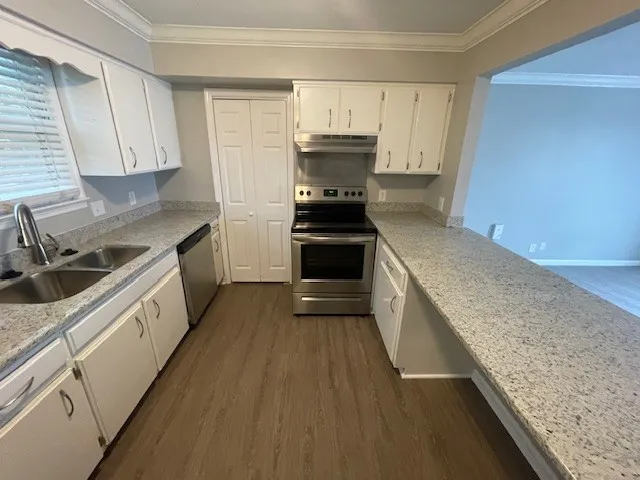 a kitchen with granite countertop a sink stove and cabinets