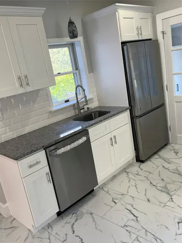 a kitchen with white cabinets appliances and a sink