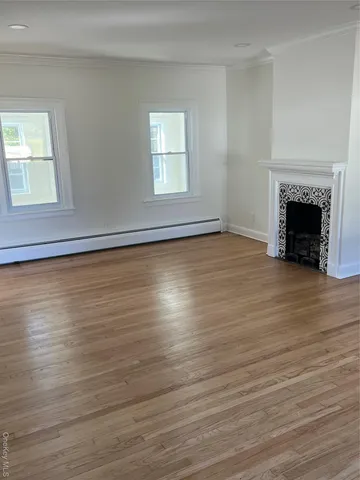 a view of empty room with wooden floor and fireplace