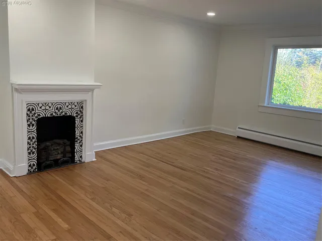 an empty room with wooden floor fireplace and windows
