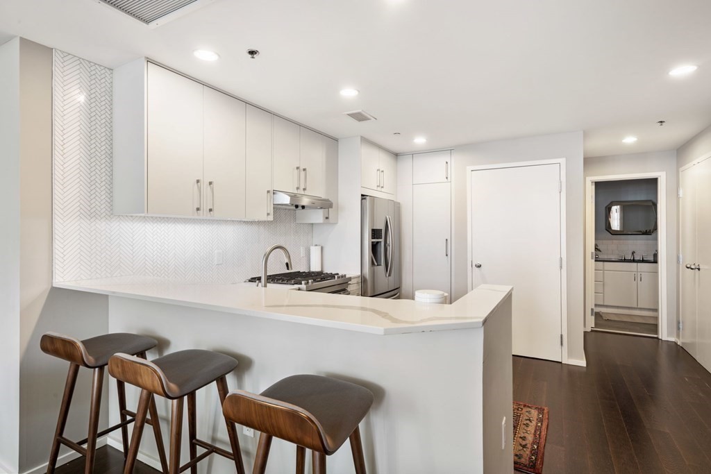 9 West Broadway, Unit 500 Boston, MA 02127 - Photo 8 of 21 a kitchen with stainless steel appliances granite countertop a white table chairs and a refrigerator