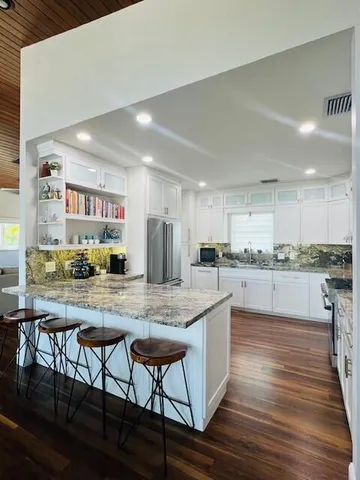 a kitchen with stainless steel appliances granite countertop a stove top oven a sink and cabinets