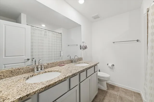 a bathroom with a granite countertop sink a toilet and a mirror