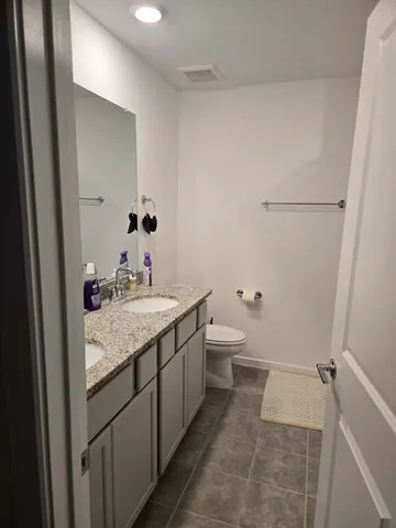 a bathroom with a granite countertop sink a toilet and mirror