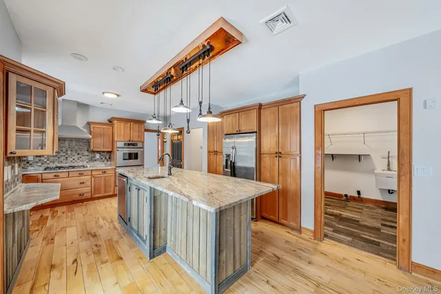 a kitchen with stainless steel appliances granite countertop a refrigerator a stove and a wooden floors