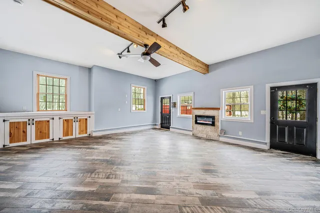a view of an empty room with window and wooden floor