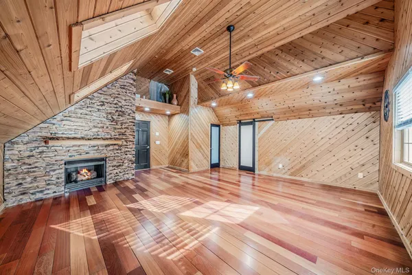 a view of an empty room with wooden floor fireplace and a window