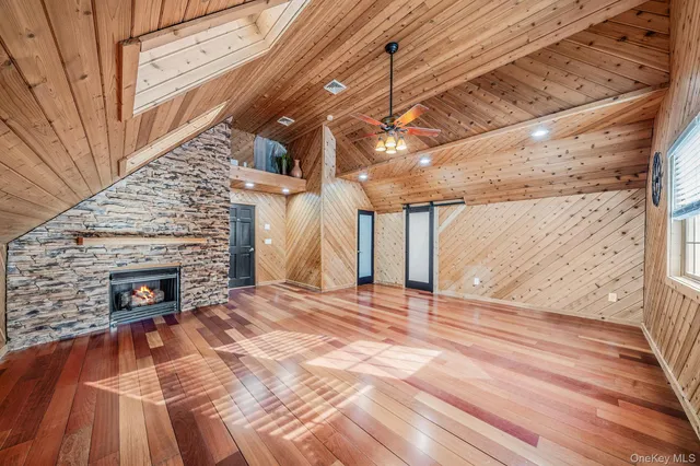 a view of an empty room with wooden floor fireplace and a window
