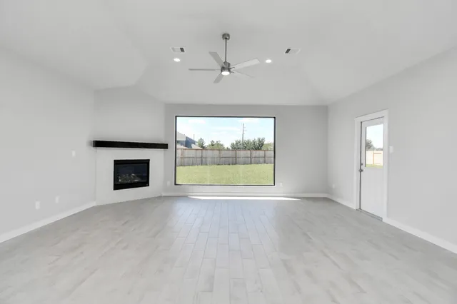 a view of an empty room with a window and wooden floor