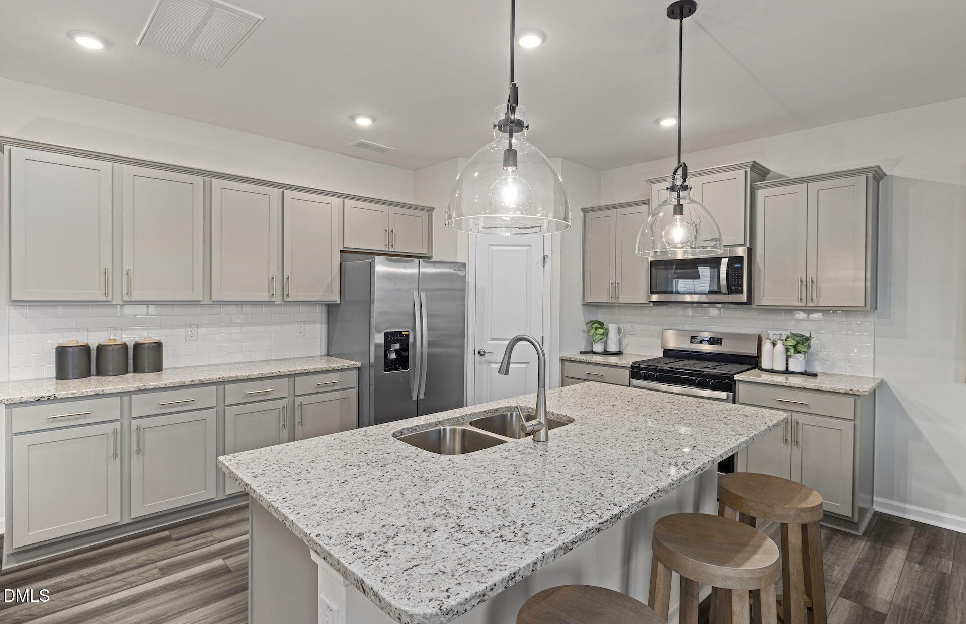 613 Ben Ledi Court Raleigh, NC 27603 - Photo 2 of 32 a kitchen with stainless steel appliances granite countertop a sink a stove a refrigerator cabinets and chairs