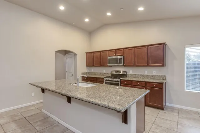 a kitchen with stainless steel appliances granite countertop a sink a stove and a microwave