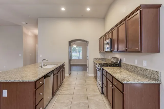 a kitchen with granite countertop sink stove and cabinets