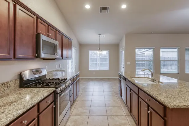 a kitchen with stainless steel appliances granite countertop a sink stove and cabinets