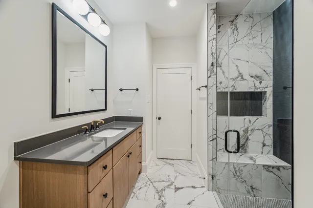 a bathroom with a granite countertop sink a mirror and shower