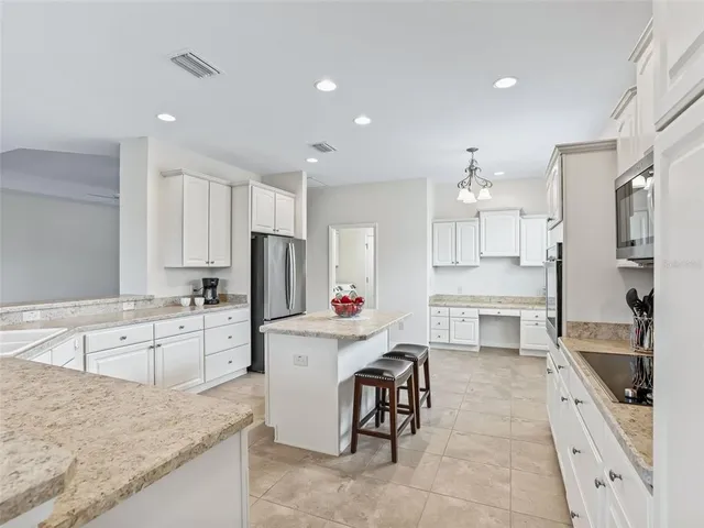 a kitchen with granite countertop a sink stove refrigerator and white cabinets with wooden floor