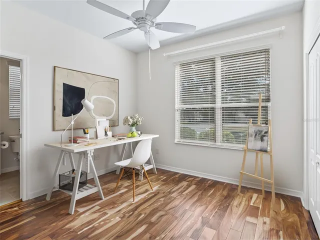 a view of empty room with wooden floor and fan