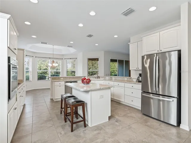 a kitchen with kitchen island a white cabinets and refrigerator