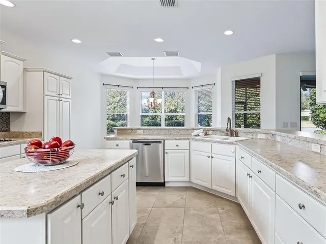 a kitchen with granite countertop a window white cabinets and stainless steel appliances