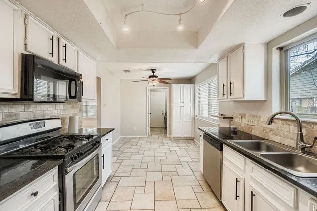 a kitchen with granite countertop a sink stove top oven and cabinets