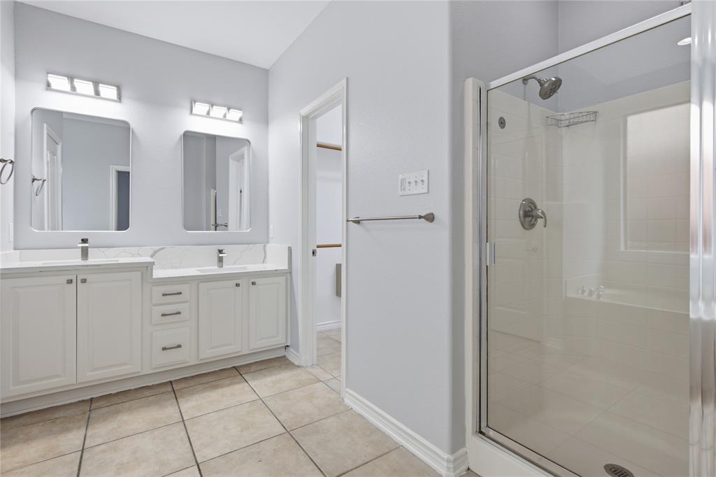 10001 Thurman Road Fort Worth, TX 76244 - Photo 20 of 40 Bathroom featuring a dual vanity with white cabinetry and integrated sinks, a glass-enclosed shower with a built-in tub, and tile flooring