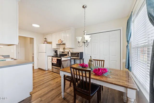 a kitchen with stainless steel appliances kitchen island granite countertop a dining table chairs and white cabinets