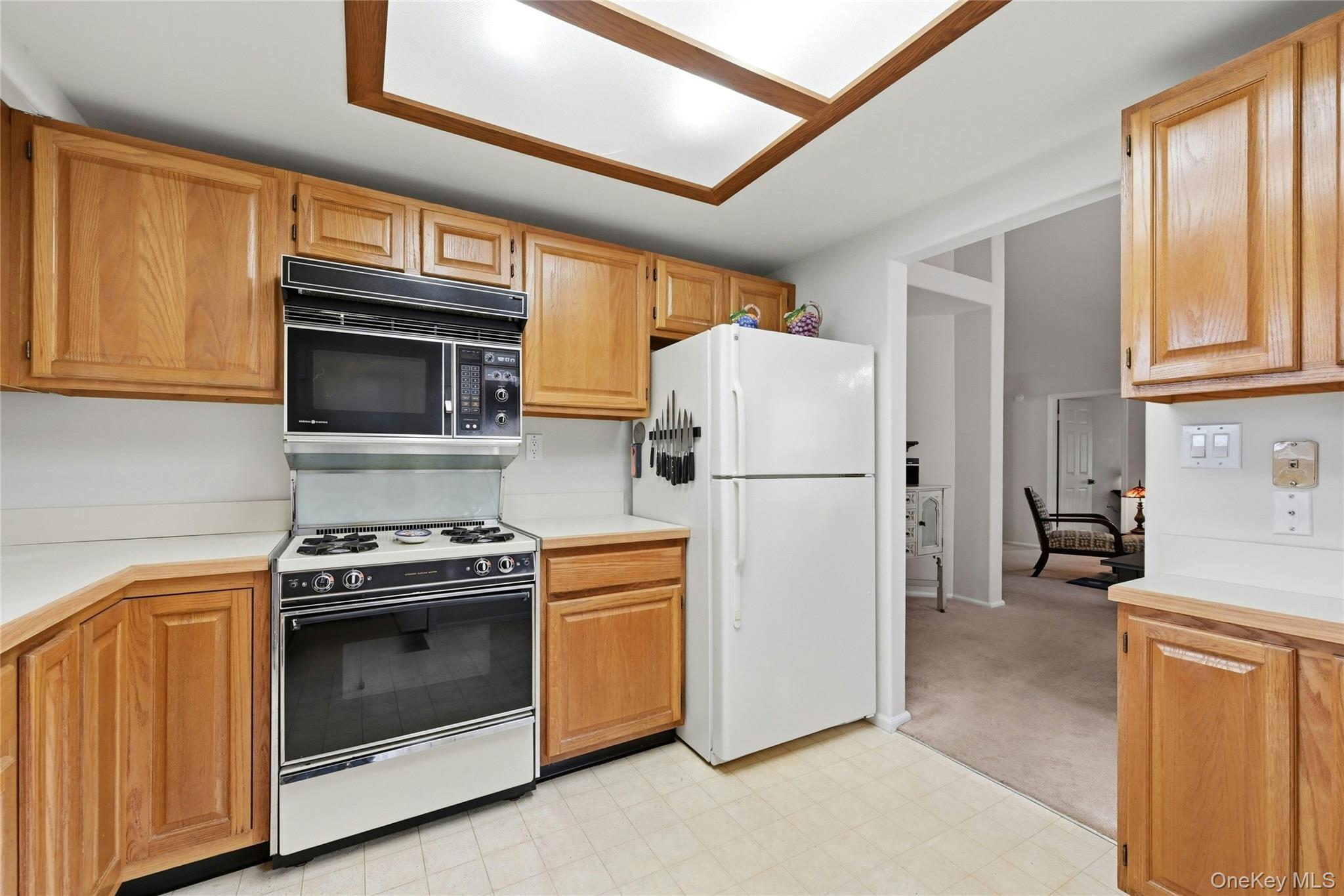 9 Baldwin Court, Unit 9 Ridge, NY 11961 - Photo 12 of 27 a kitchen with refrigerator a stove a microwave and cabinets
