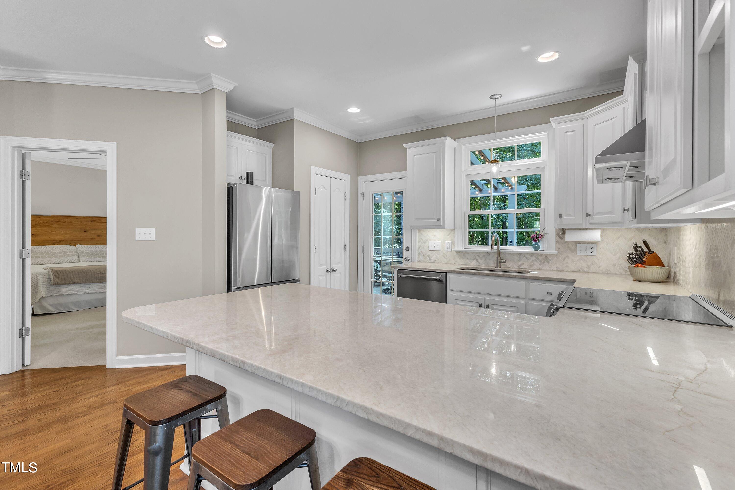 6323 Cedar Waters Drive Raleigh, NC 27607 - Photo 24 of 84 a kitchen with stainless steel appliances a refrigerator a sink a stove and white cabinets with wooden floor