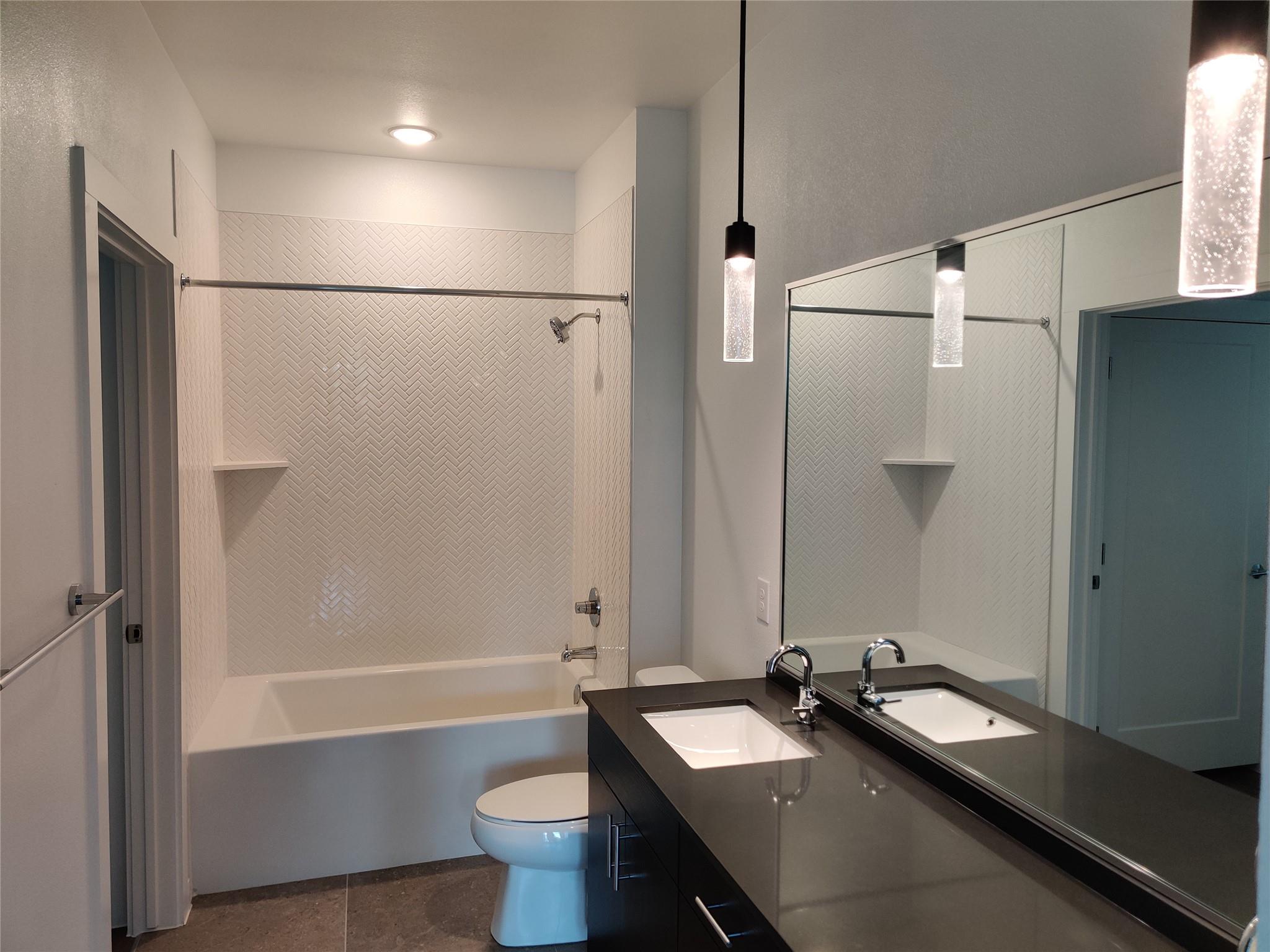 4801 Springdale Road, Unit 1102 Austin, TX 78723 - Photo 7 of 18 Herringbone shower wall tile and solid stone counters elevate this modern bathroom design.
